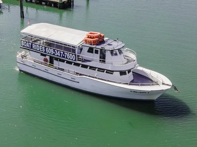 Weißes Ausflugsboot namens 'CRUISN I' auf grünem Wasser aus der Vogelperspektive