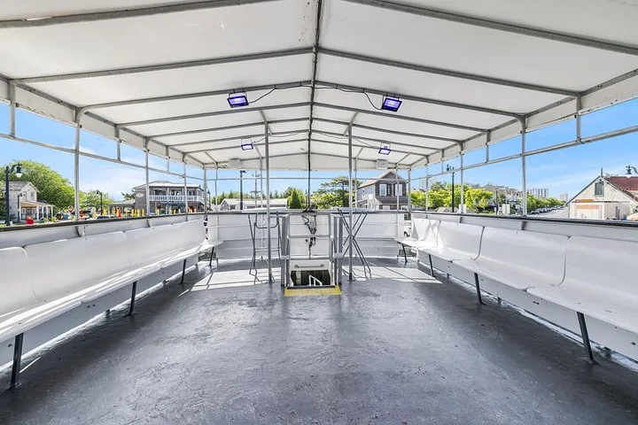 Covered upper deck of a tour boat with white bench seating along the sides